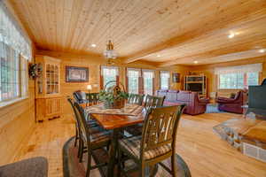Dining space with wood ceiling, light wood-style flooring, wood walls, visible vents, and recessed lighting