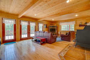 Living room with french doors, wood ceiling, wood walls, and light wood-style flooring
