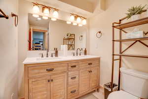 Bathroom featuring a sink, double vanity, and toilet