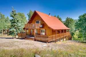 Back of property with a deck, metal roof, and a balcony