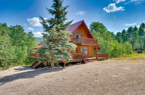 View of front of home with a wooden deck, metal roof, and a balcony