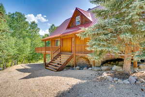 View of front of house featuring metal roof, stairway, and a wooden deck