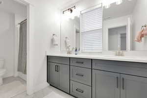 Full bath featuring toilet, marble finish floor, baseboards, and a sink