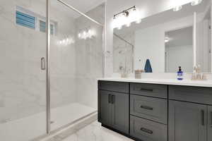 Bathroom with a shower stall, marble finish floor, double vanity, and a sink