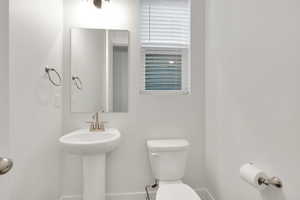 Bathroom featuring toilet, baseboards, and a sink