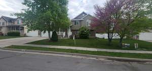 Obstructed view of property with driveway, stucco siding, a front yard, and a garage