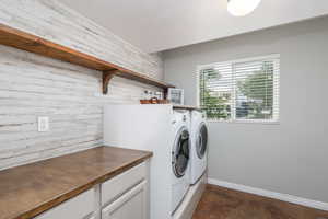Washroom with washer and clothes dryer, a textured ceiling, wooden walls, and baseboards