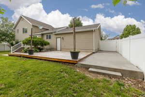 Back of house featuring a deck, a shingled roof, and a patio