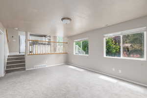 Spare room with carpet floors, baseboards, stairway, and a textured ceiling