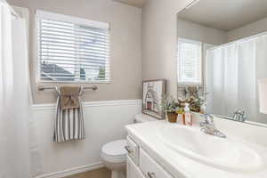 Bathroom with wainscoting, toilet, vanity, a shower with curtain, and tile patterned floors