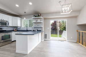 Kitchen with appliances with stainless steel finishes, a sink, dark countertops, decorative backsplash, and plenty of natural light