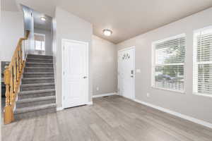 Entrance foyer featuring light wood-style floors, baseboards, and stairs