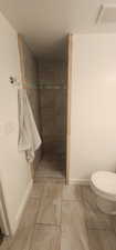 three quarterl bath featuring a tile shower, toilet, baseboards, and visible vents