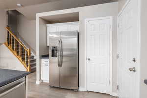 Kitchen featuring appliances with stainless steel finishes, light wood-type flooring, white cabinets, and baseboards