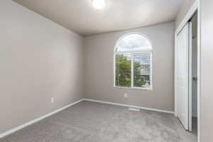Unfurnished bedroom featuring light colored carpet, a closet, and baseboards