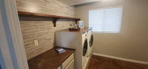 Laundry room featuring baseboards, wood walls, separate washer and dryer, and a textured ceiling