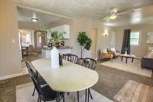 Carpeted dining space with a textured ceiling, baseboards, and a ceiling fan