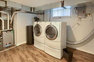 Washroom with electric panel, independent washer and dryer, light wood finished floors, and baseboards