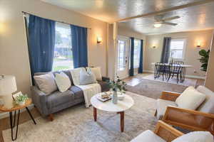 Living area featuring light carpet, ceiling fan, and baseboards