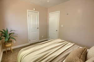 Bedroom with carpet, baseboards, and a textured ceiling
