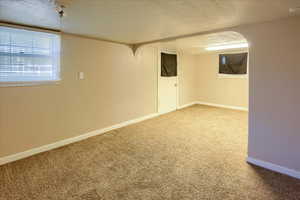 Below grade area featuring carpet floors, baseboards, and a textured ceiling