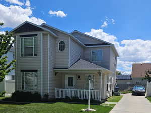 View of front of house with driveway, a porch, a front lawn, and fence