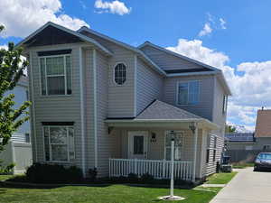 View of front of home featuring a porch, fence, a front lawn, and concrete driveway