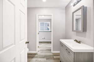 Bathroom featuring wood finished floors, vanity, toilet, and baseboards