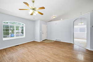 Living room with  wood finished floors, vaulted ceiling, ceiling fan, arched walkway