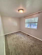 First bedroom with carpet flooring and freshly painted.