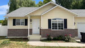 View of front facade featuring a shingled roof, brick siding, and an attached garage