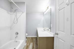 Full bath featuring vanity, toilet, wood finished floors, washtub / shower combination