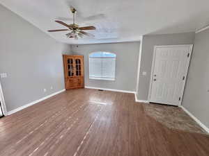 Foyer entrance in living room area with wood finished floors, a vaulted ceiling with fan