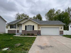 Ranch-style house featuring driveway, brick siding, fence, a garage, and a front yard