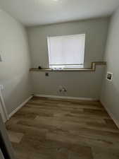Washroom featuring gas dryer hookup, hookup for a washing machine, wood finished floors, laundry area, and electric dryer hookup