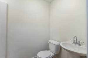 Half bath with toilet, baseboards, and a sink