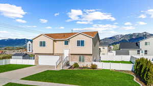 Bi-level home with a mountain view, driveway, a front lawn, and brick siding