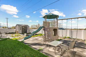 View of play area featuring a storage shed, an outbuilding, and a fenced backyard