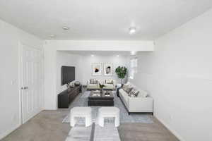 Living room with carpet floors, a textured ceiling, and baseboards