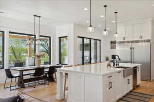 Kitchen featuring a sink, light wood-style floors, white cabinetry, light countertops, and appliances with stainless steel finishes