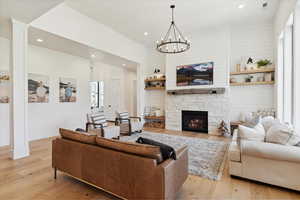 Living room with visible vents, recessed lighting, a fireplace, an inviting chandelier, and light wood-style floors