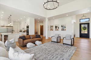 Living area with light wood-style floors, a chandelier, recessed lighting, and decorative columns