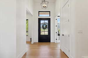 Foyer with a chandelier, light wood-style flooring, baseboards, and a towering ceiling