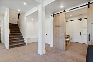 Below grade area featuring light carpet, a barn door, and recessed lighting