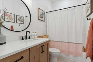 Bathroom featuring toilet, vanity, and shower / tub combo