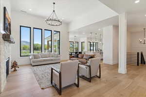 Living area with visible vents, baseboards, light wood-style flooring, and a notable chandelier