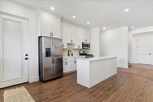 Kitchen with a sink, stainless steel appliances, tasteful backsplash, white cabinetry, and light countertops