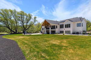 Back of property featuring central air condition unit, a lawn, and a balcony
