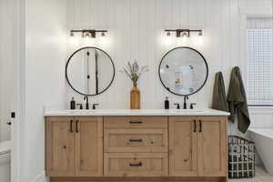 Full bath featuring double vanity, a freestanding bath, toilet, and a sink
