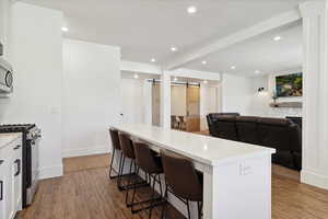 Kitchen featuring stainless steel microwave, wood finished floors, a breakfast bar, a barn door, and range with gas cooktop